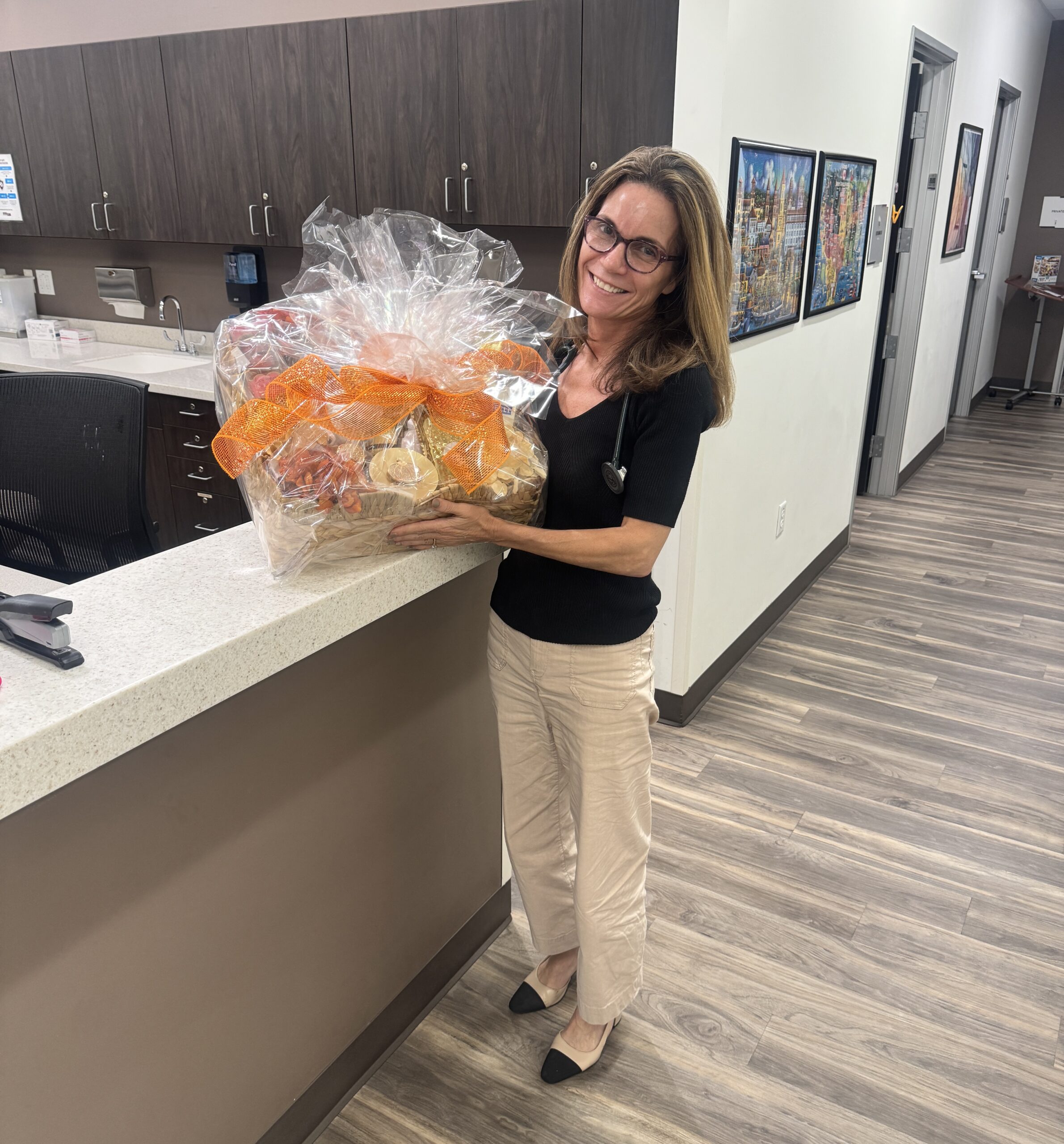 Networking bingo winner, Dr. Djurisic, holding gift basket at her practice. 