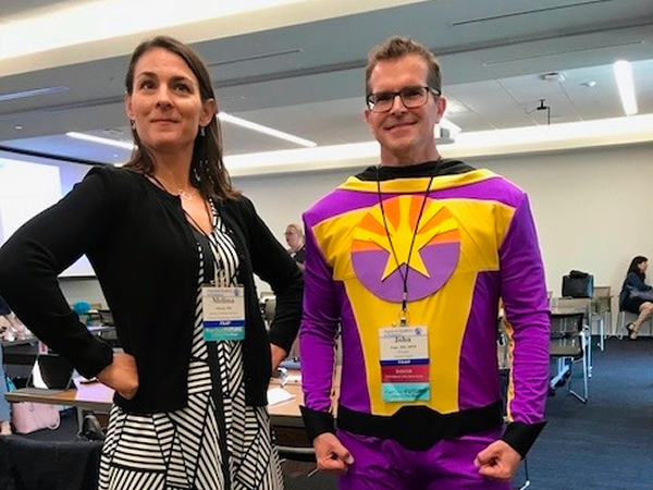 John Pope, MD in superhero costume alongside wife in superhero pose